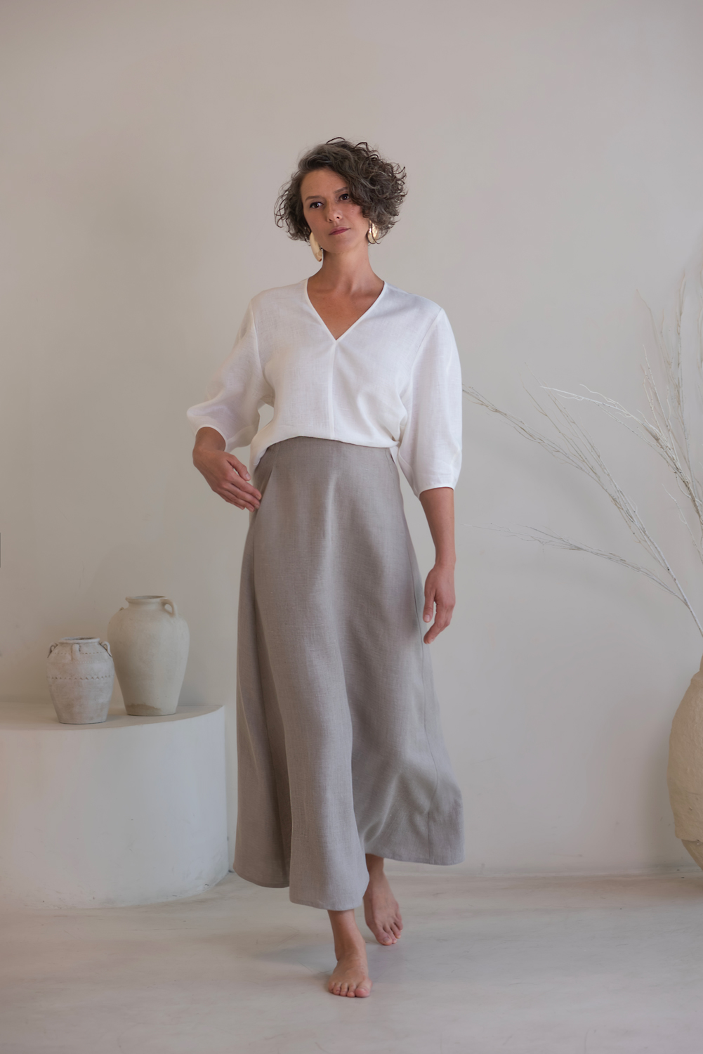 Minimalist linen outfit featuring a relaxed white V-neck top paired with a flowing gray maxi skirt for an elegant, natural look. Women's linen two-piece set with white V-neck top and gray maxi skirt