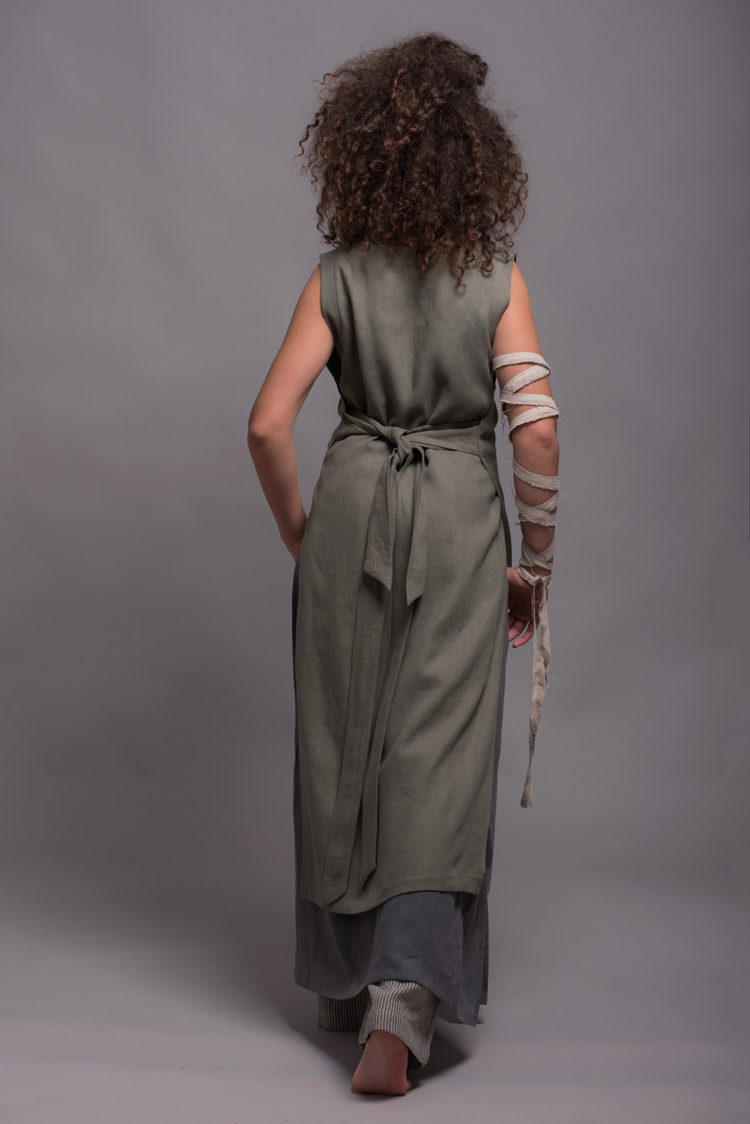 Back view of the LINAS apron dress, emphasizing the natural flow of medium-weight linen fabric.
