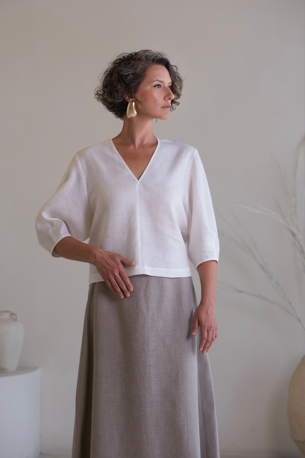 Detailed view of the white linen top featuring a flattering V-neckline, relaxed fit, and comfortable three-quarter-length sleeves. White linen blouse for women with V-neck and three-quarter sleeves