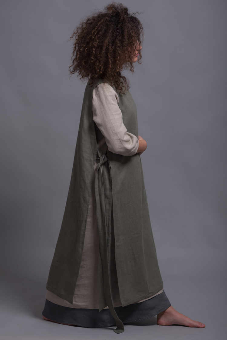 Side view of the LINAS linen pinafore dress layered over a lightweight tunic, showing its versatility.