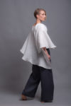 Asymmetric hem detail of the white linen top, highlighting the flowing design.