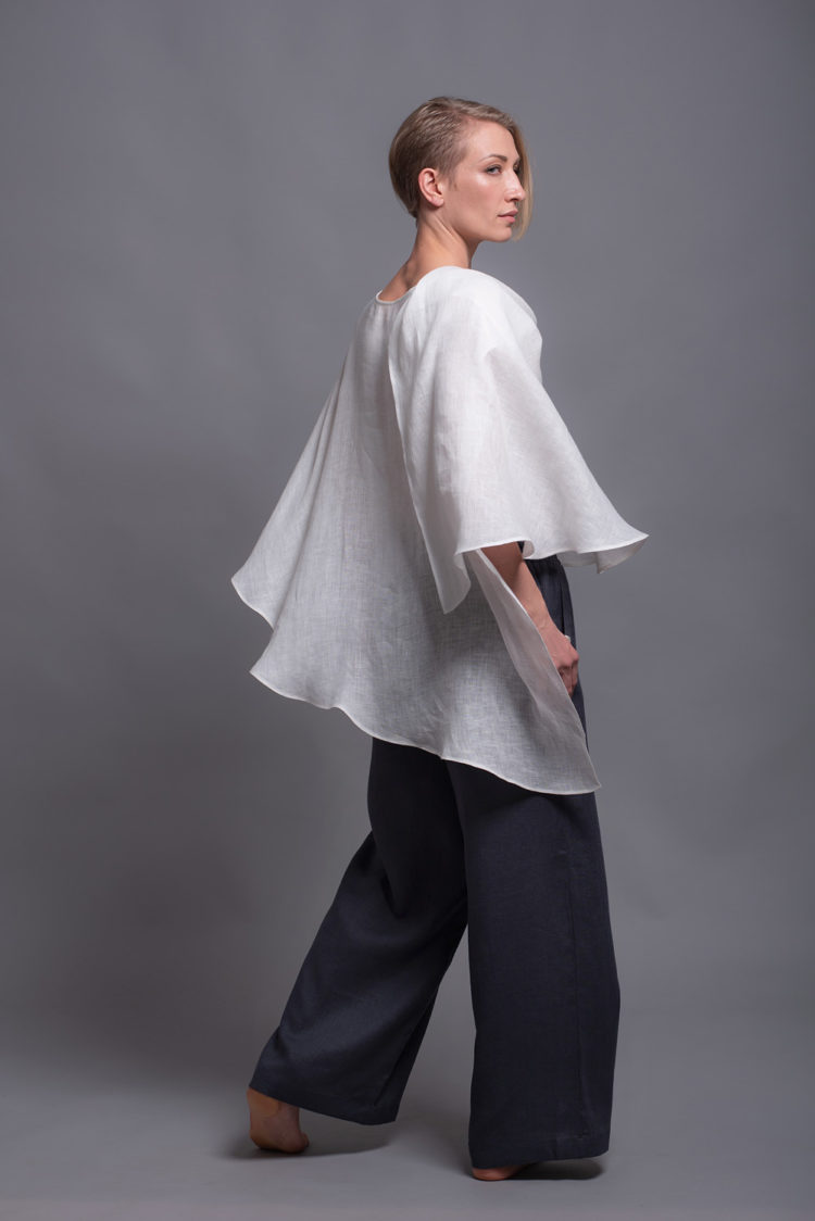 Asymmetric hem detail of the white linen top, highlighting the flowing design.