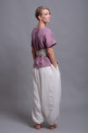 Loose linen blouse TOD paired with white harem pants and belt for a minimalist summer outfit.