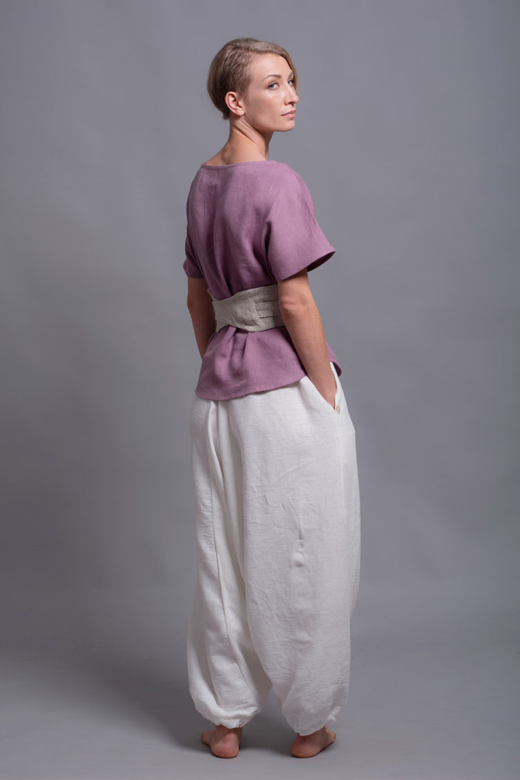 Loose linen blouse TOD paired with white harem pants and belt for a minimalist summer outfit.