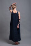 Model wearing a sleeveless linen maxi dress with arm tie details, styled in a minimalist and bohemian look.