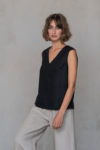 Model showcasing the V-Neck Linen Sleeveless Blouse in a modern, minimalist setting, highlighting its versatile style