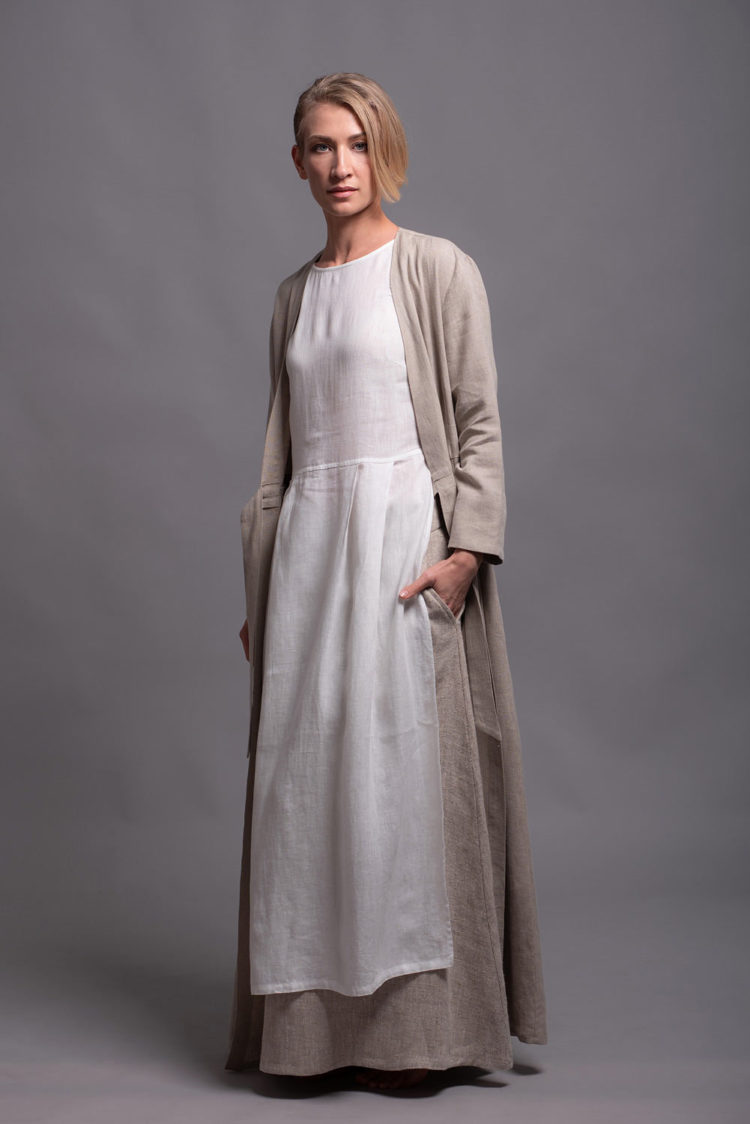 Model wearing the white tunic dress layered over linen skirt with long jacket for a casual look.